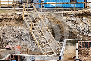 Descent into a deep pit during the construction of a house. Building safety. Ladder for descending to reinforced concrete