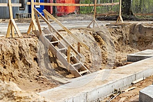 Descent into a deep pit during the construction of a house. Building safety. Ladder for descending to reinforced concrete