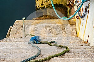 Descent down to the ocean in a fishing port, old cords and ropes