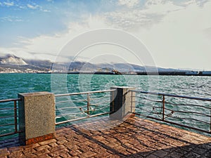 Descent to the sea. The waves. A pier and part of an industrial port. Mountain range. Floating clouds in the sky.