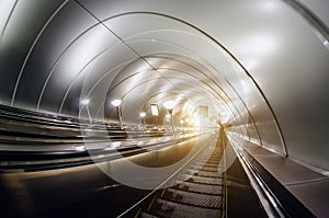 Descent into the tunnel stereo escalator stairs light from below.