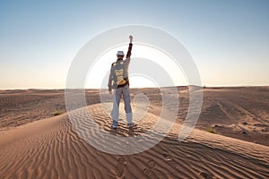 Desert adventure. Young man with backpack walking on sand dune. Dubai, United Arab Emirates