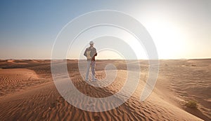 Desert adventure. Young man with backpack walking on sand dune. Dubai, United Arab Emirates