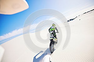 Desert, back and man on motorcycle for sport, adventure and travel for extreme challenge outdoor. Off road, sand and