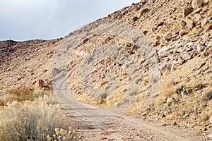 Desert dirt road ascending rocky hillside