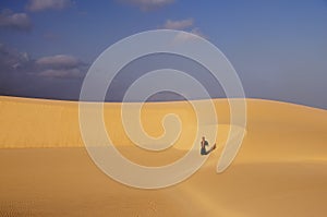 Desert, dunes, blue sky, sunny day in the distance a traveler