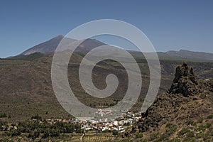 Desert landscape in the Canary Islands with a background of the volcano Teide and small white houses.