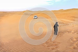 Desert landscape in Dubai with a woman and a desert safari car