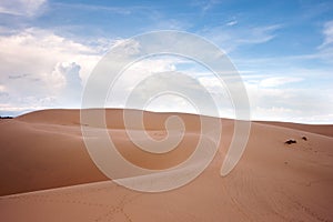 Desert landscape dunes in the afternoon with blue skies white clouds.