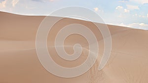 Desert landscape dunes in the afternoon with blue skies white clouds.