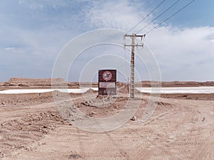 Desert landscape featuring an empty dirt road with a signpost in the foreground