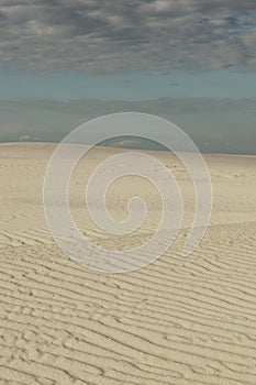 Desert landscape.  White sand, dunes and blue sky with clouds.  Background with sand texture