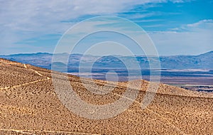 Desert plains with valley and mountains beyond under a blue sky