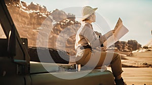 Desert Road Trip: Beautiful Female Traveler Checking Map while Sitting on a Hood of Her Offroad SUV