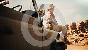 Desert Road Trip: Beautiful Female Traveler Looking Around while Sitting on a Hood of Her Offroad