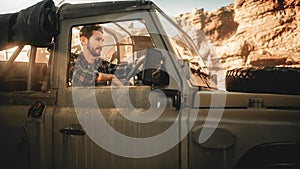 Desert Road Trip: Portrait of Handsome Male Explorer Looking out of Car Driver Window and Smiling