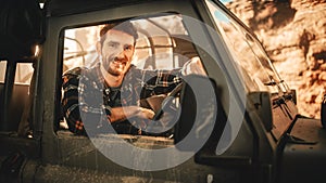 Desert Road Trip: Portrait of Handsome Male Explorer Looking out of Car Driver Window and Smiling