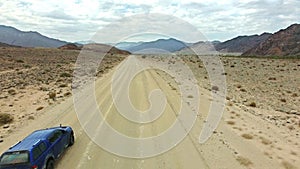Desert, road trip and truck on adventure in mountains with nature, freedom and transport in drone shot. Rally driving