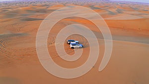 Desert Safari off-roading, group of jeep or SUV or 4x4 car vehicle rides on desert dune barkhan or sand-dune. Aerial