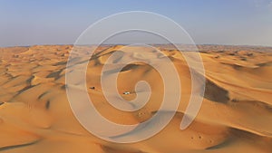 Desert Safari off-roading, group of jeep or SUV or 4x4 car vehicle rides on desert dune barkhan or sand-dune. Aerial