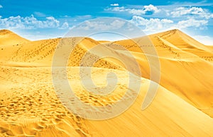 Desert with sand dunes and clouds on blue sky