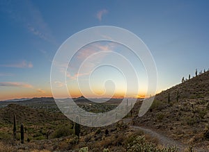 A desert trail on a mountain leading to a sunset over a valley in Phoenix