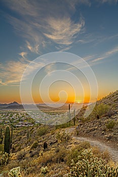 A desert trail on a mountain leading to a sunset over a valley in Phoenix