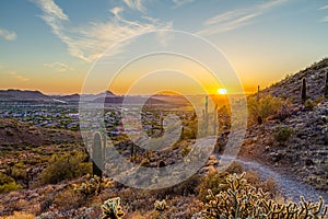 A desert trail on a mountain leading to a sunset over a valley in Phoenix