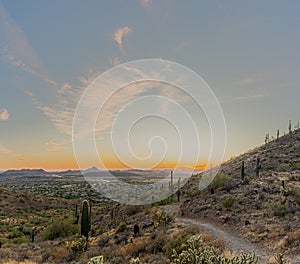 A desert trail on a mountain leading to a sunset over a valley in Phoenix