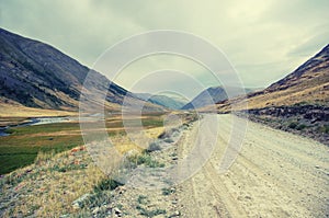 Desert tundra high mountain river valley with dusty road