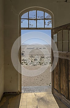 desert view through forsaken hospital door at mining ghost town in desert, Kolmanskop, Namibia