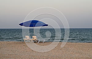 Deserted beach with deckchairs and parasol