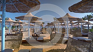 A deserted beach in the early morning, beach umbrellas and sun loungers are empty.