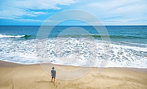 Deserted beach and lone watching man, person stands alone on sea sand shore