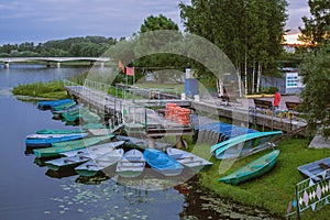 Deserted boat station at dusk. Pier by the water, lifebuoys and boats. Evening landscape