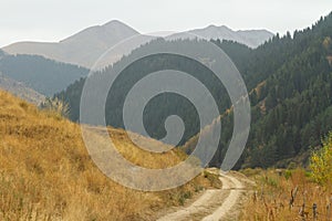 Deserted dusty country road near the autumn mountains