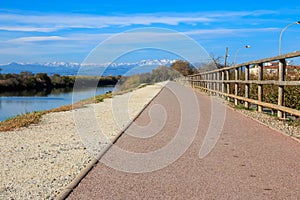 Deserted gravel hiking path with snowy mountains peaks in background