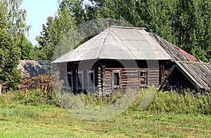 A deserted house without windows is standing among the tall grass
