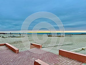 Deserted Mediterranean Beach at Sunrise with Cloudy Sky, Calm Waves, and Empty Structures on the Shoreline in Palavas-les-Flots, photo