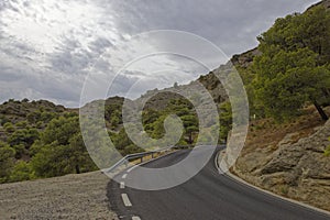 A deserted narrow winding road passing through the Mountain Scenery of central Andalusia.