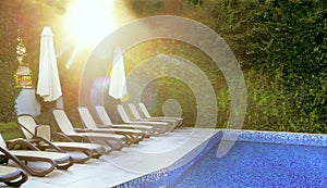 Deserted pool and sun loungers by the pool in the gentle rays of the morning sun. Place of rest and relaxation, summer mood.