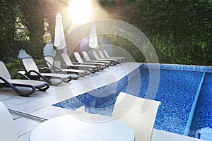 Deserted pool and sun loungers by the pool in the gentle rays of the morning sun. Place of rest and relaxation,