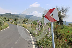Deserted road leading to Sirince village with a central left turn sign