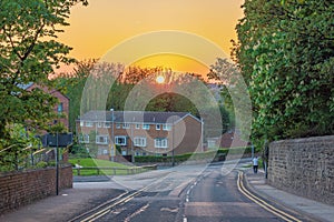 Deserted road at sunset with yellow sky over a quaint town