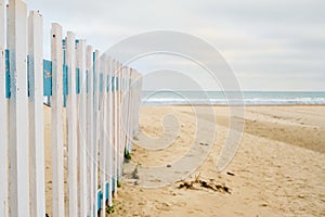 Deserted spring beach, fence in front of a public beach, cloudy sky in anticipation of rain. Off-season sea beach, place for text