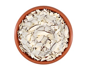 Desiccated coconut chips in an earthenware bowl.