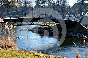 Design arch bridge over a pond made of steel lattice girders. gray transparent railing combined with concrete. Japanese style rive