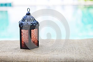 Design black Morrocan Metal Lantern with red glass on swimming poool edge