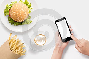 Design concept of mockup using smartphone with burger, french fries and coffee set on white background.