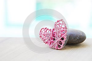 Design pink wooden heart with stone over blurred background, outdoor day light